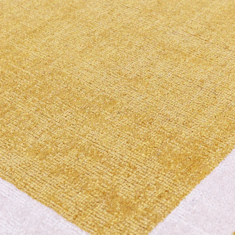 Close-up of yellow textured area rug with cream border on floor