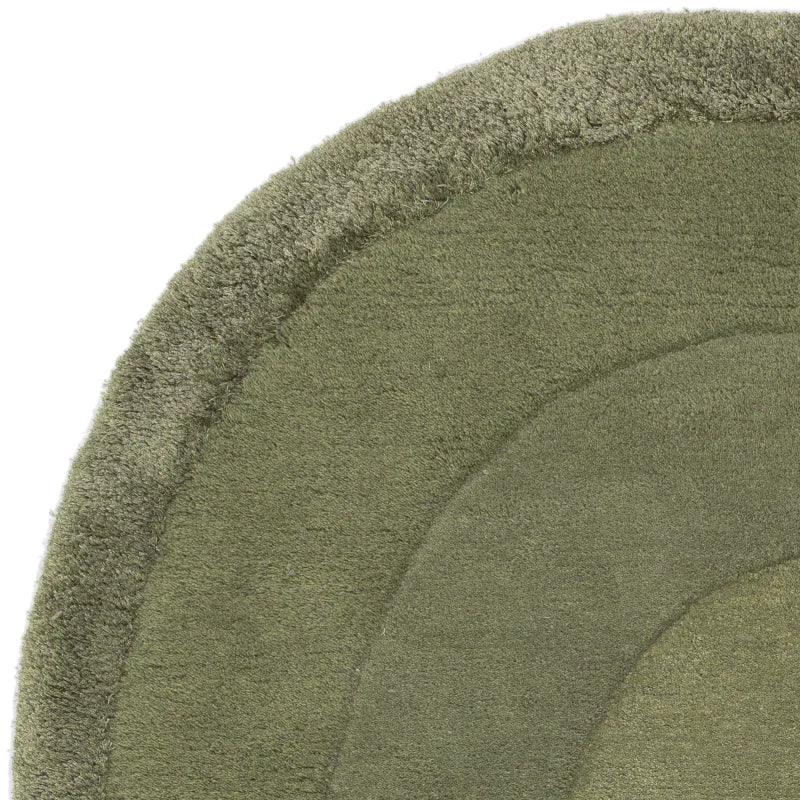 Close-up of green area rug with textured border and curved pattern
