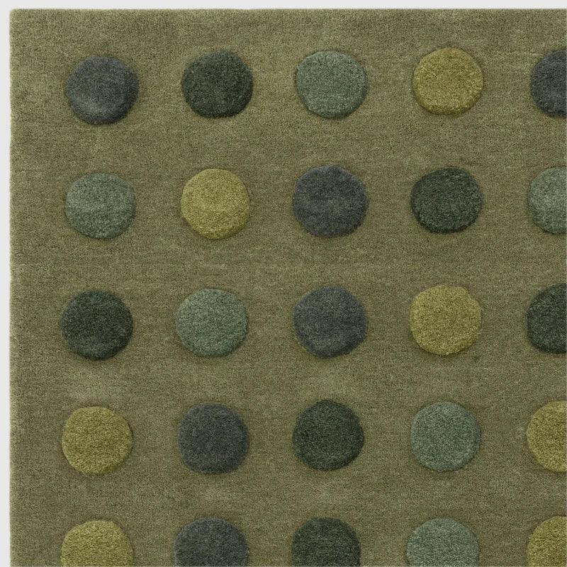 Green wool rug with raised polka dot pattern in various shades, close-up view
