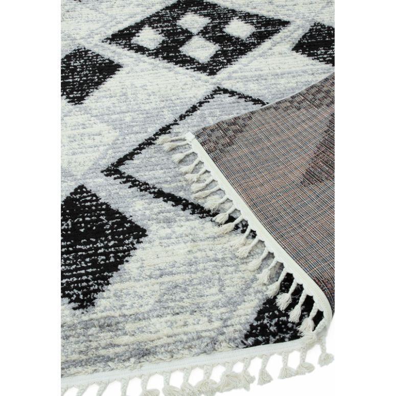 Monochrome geometric area rug with tassel fringe, close-up on corner and pattern detail