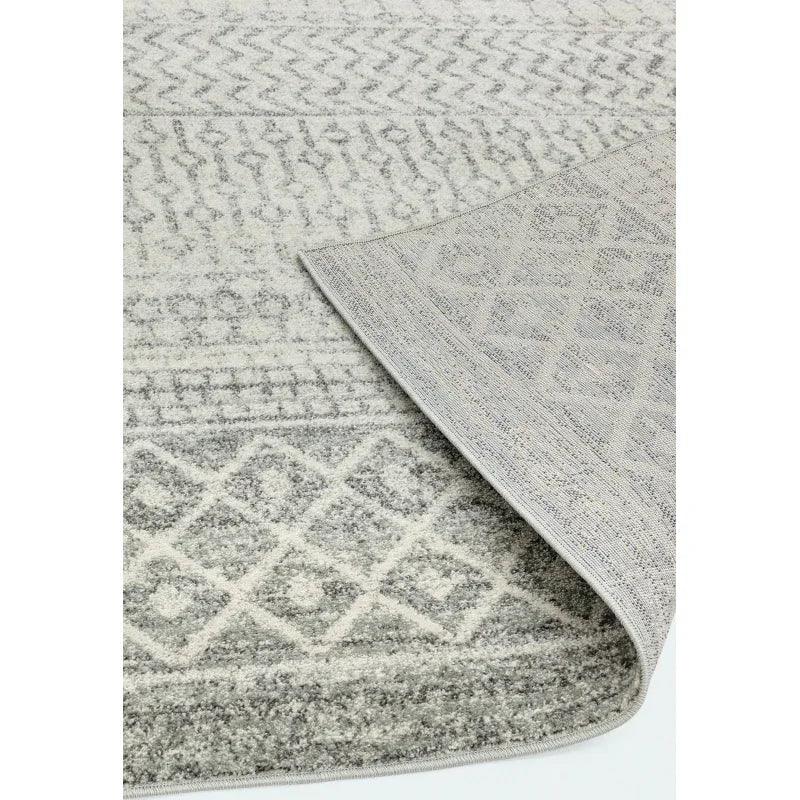 Grey patterned area rug with geometric and zigzag designs, close-up of corner detail