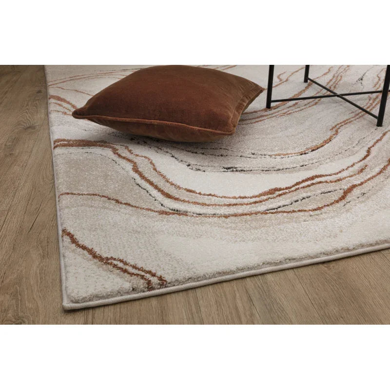 Cream and brown abstract rug with brown velvet cushion on wooden floor