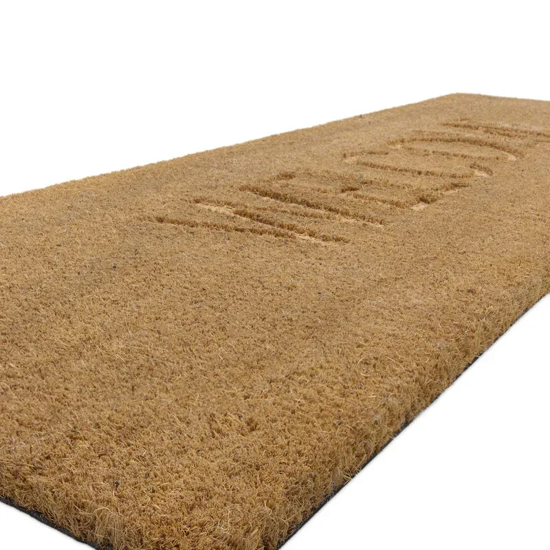 Natural coir doormat with embossed welcome text, angled side view