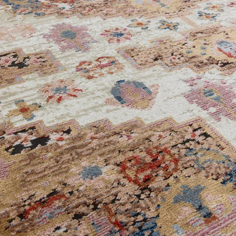 Close up of patterned living room rug with beige, pink, blue and brown geometric designs
