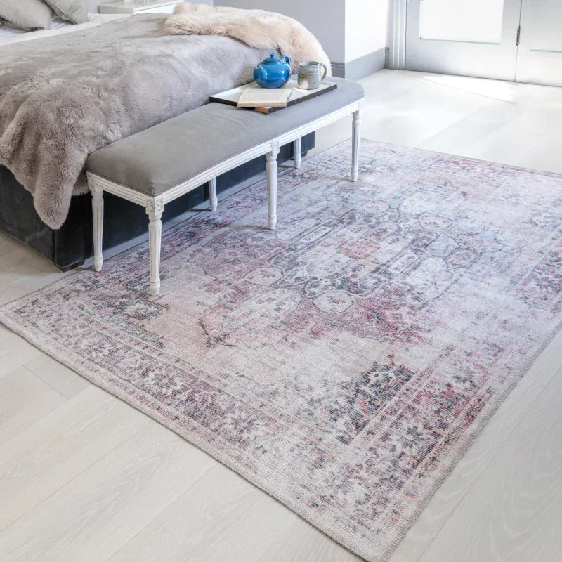 Vintage style area rug with faded pink and grey pattern in bedroom setting