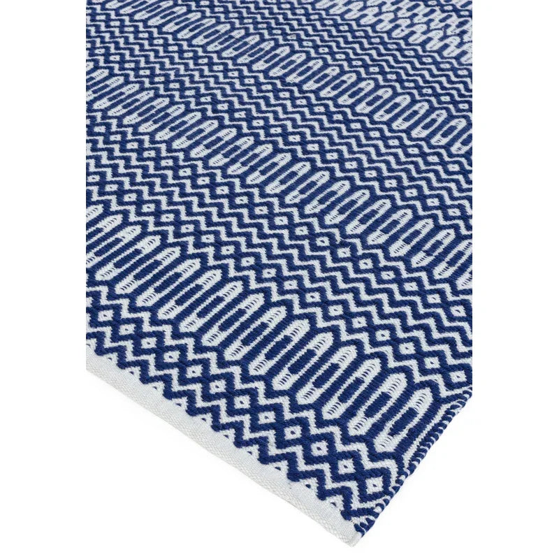 Blue and white geometric patterned rug corner with textured woven design
