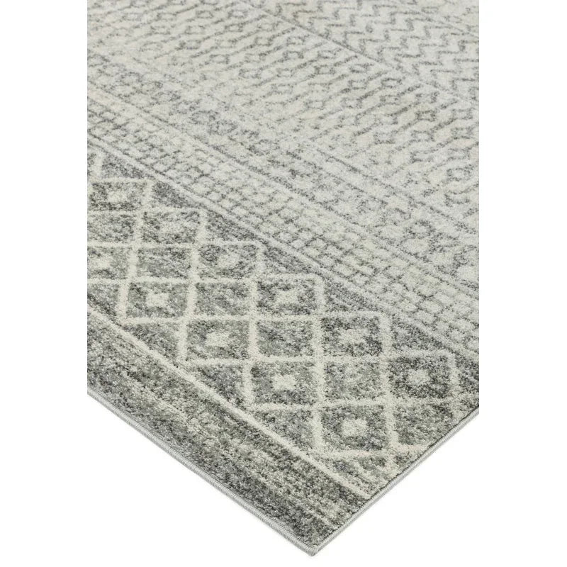 Grey patterned area rug with geometric and zigzag designs, close-up corner view