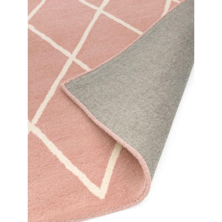 Pink area rug with white geometric lines and visible grey woven backing corner