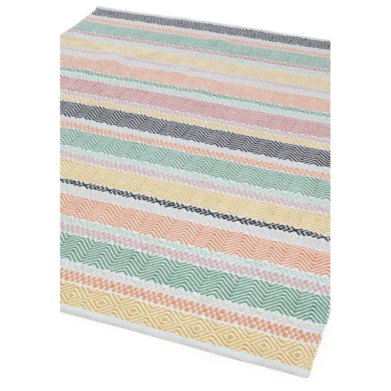 Multicolour patterned rug with geometric stripes in pastel shades, close-up corner view