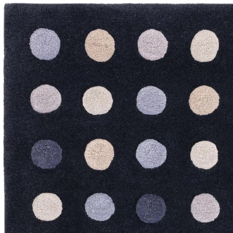 Black area rug with beige and grey polka dot pattern, closeup of textured surface
