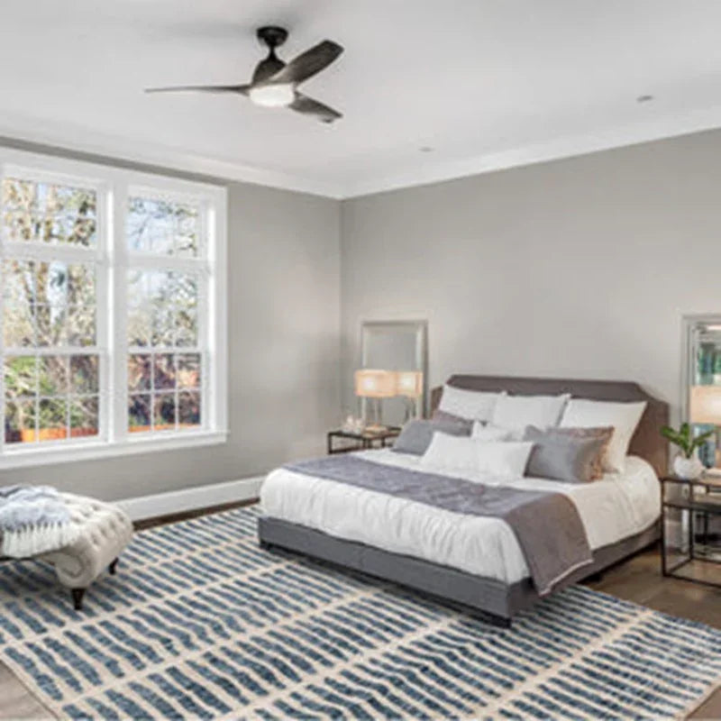 Modern grey upholstered bed with white bedding and pillows in a bright bedroom