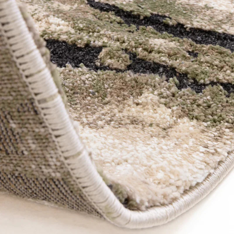 Close-up of beige and green patterned rug with textured pile and stitched edge