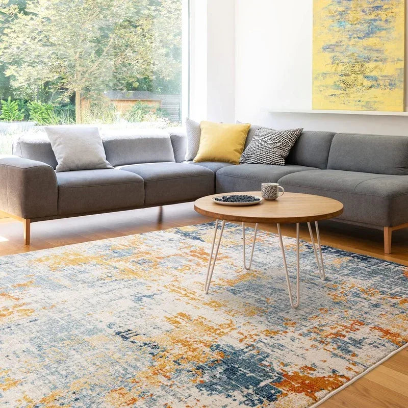 Grey corner sofa with modern cushions, round wooden coffee table and abstract patterned rug