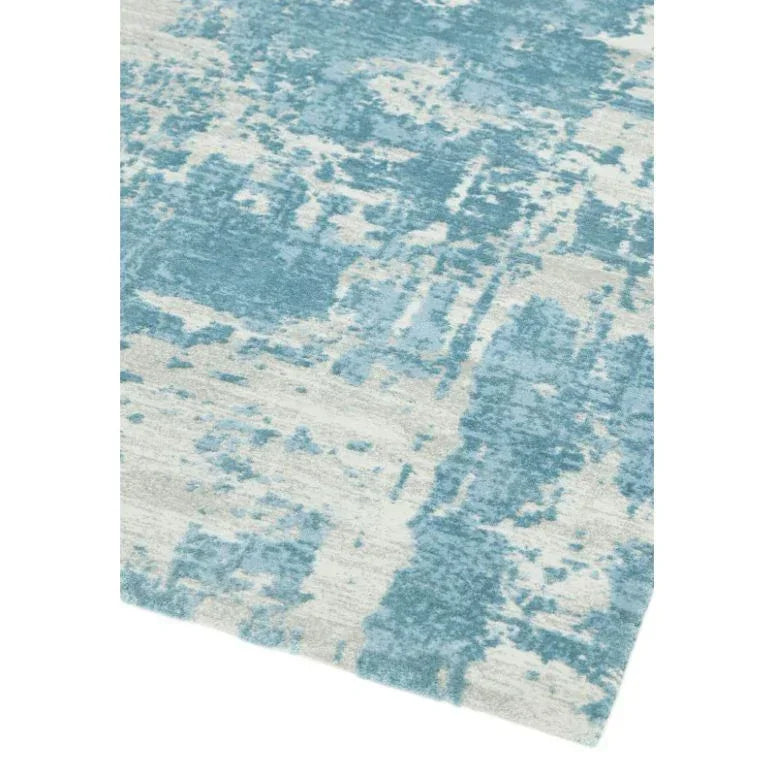 Blue and cream abstract patterned rug corner with textured surface