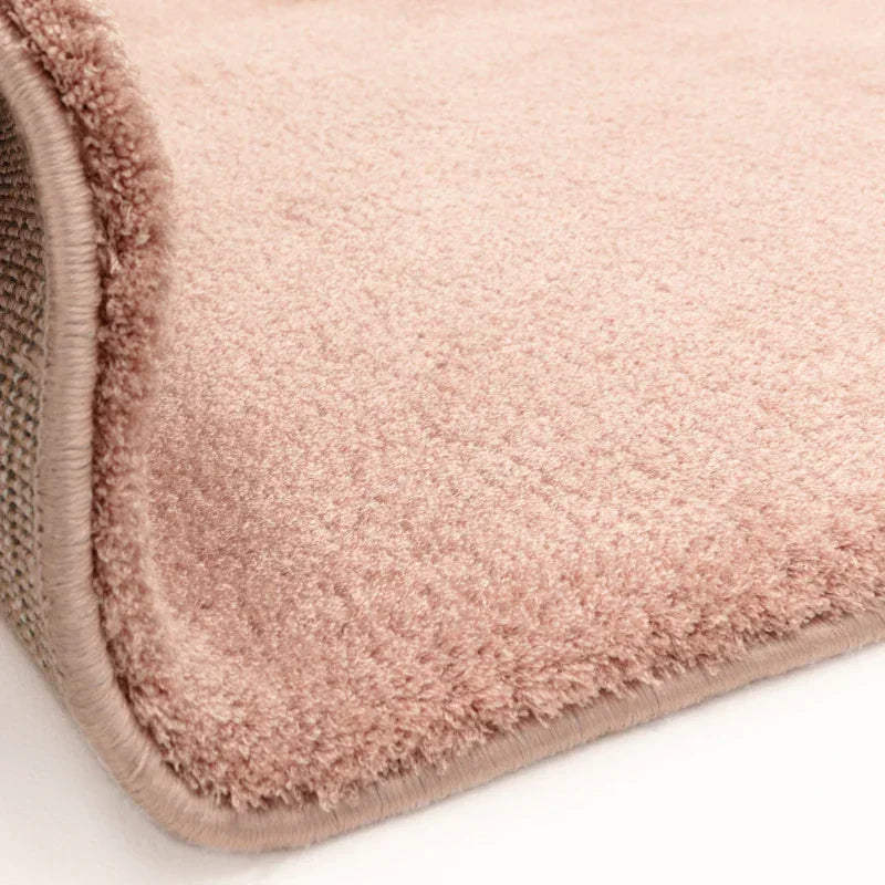 Close-up blush pink rug with soft texture and stitched edge detail