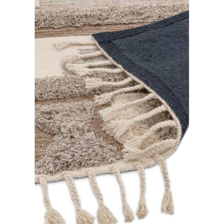 Textured beige and cream rug with tasselled fringe and geometric pattern, corner flipped up