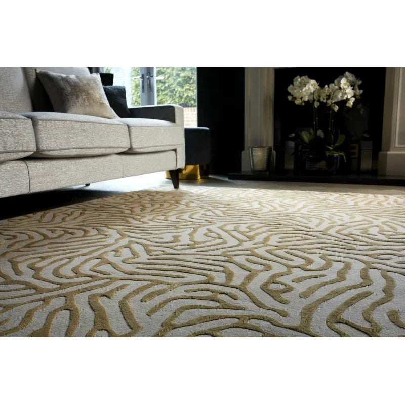 Modern beige patterned area rug in living room with grey sofa and floral decor