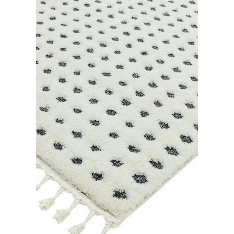 cream area rug with black dot pattern and tasseled edge corner view