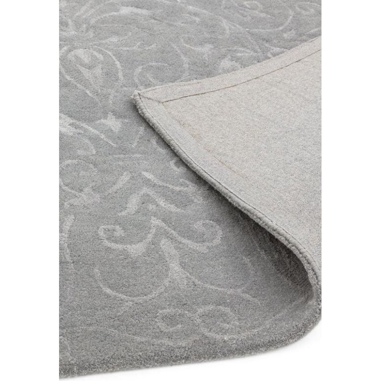 Grey patterned rug with subtle floral design and folded corner showing backing