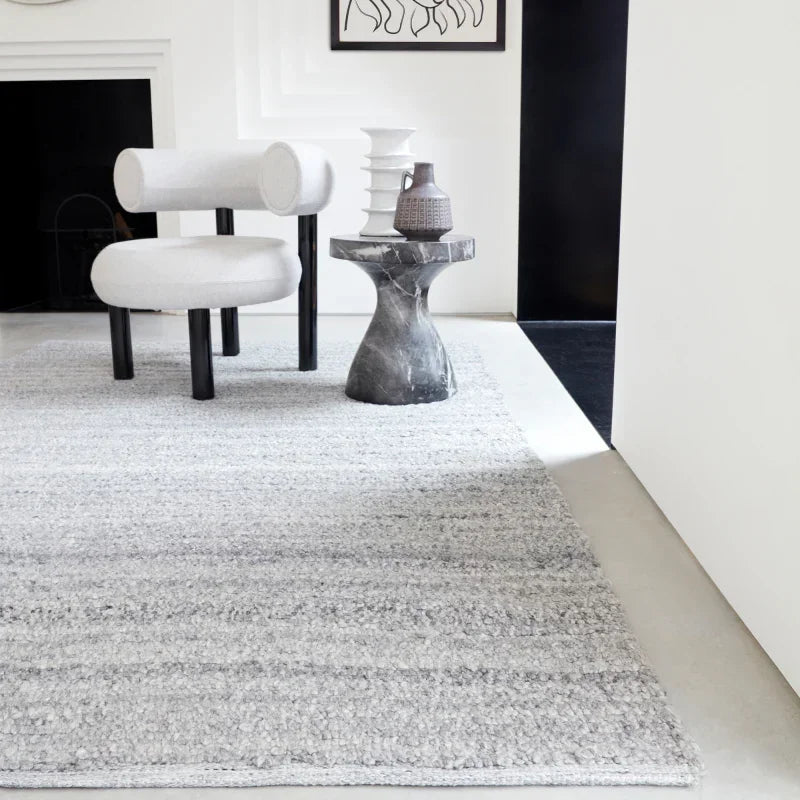 Light grey textured rug with modern chair and stone side table in contemporary living room