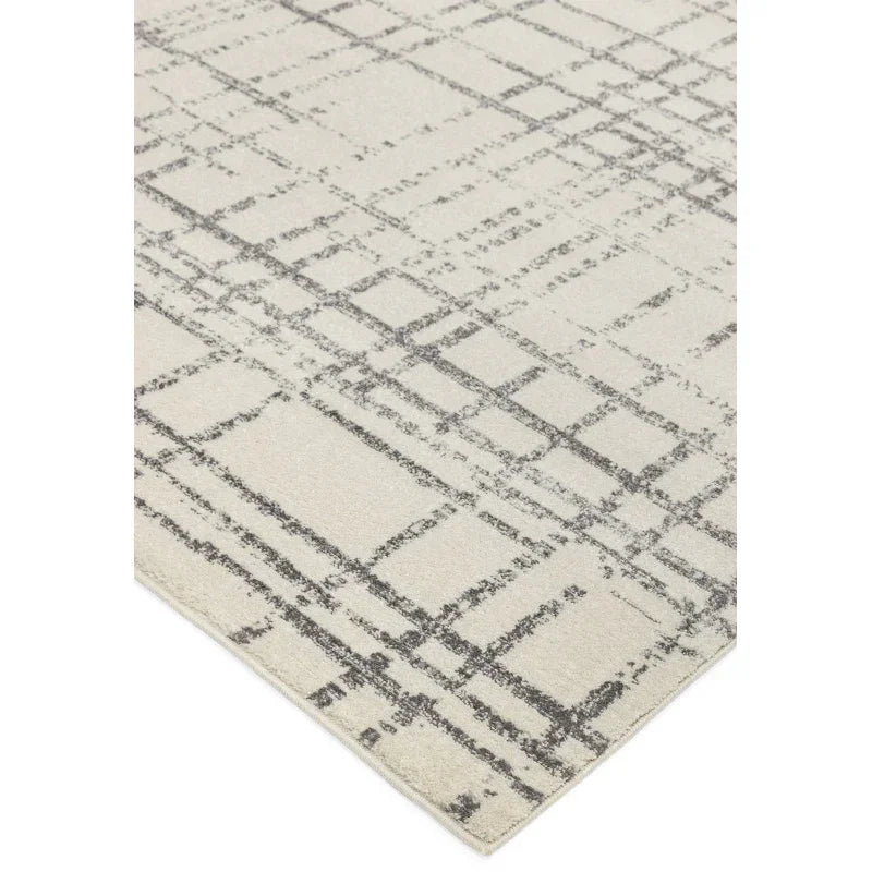 Modern area rug with abstract grey line pattern on cream background, angled corner view