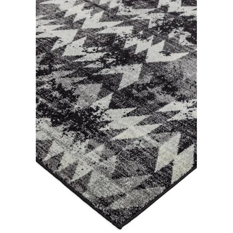 Grey geometric rug with zigzag pattern and textured surface, corner angled view