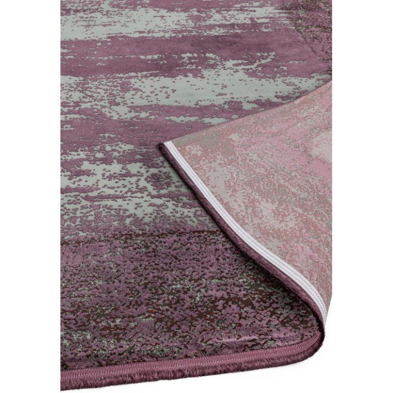 Purple and grey abstract area rug with visible corner fold showing underside