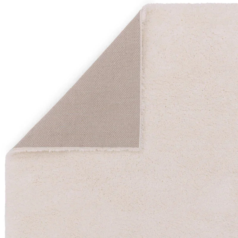 Ivory area rug corner flipped to show textured non-slip backing