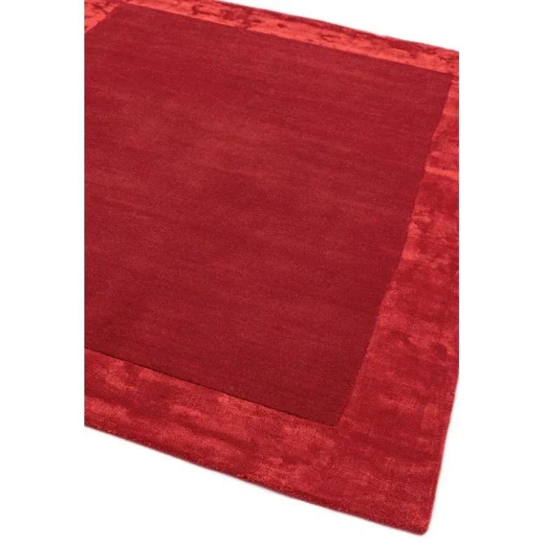 Red area rug with solid center and textured border on white background