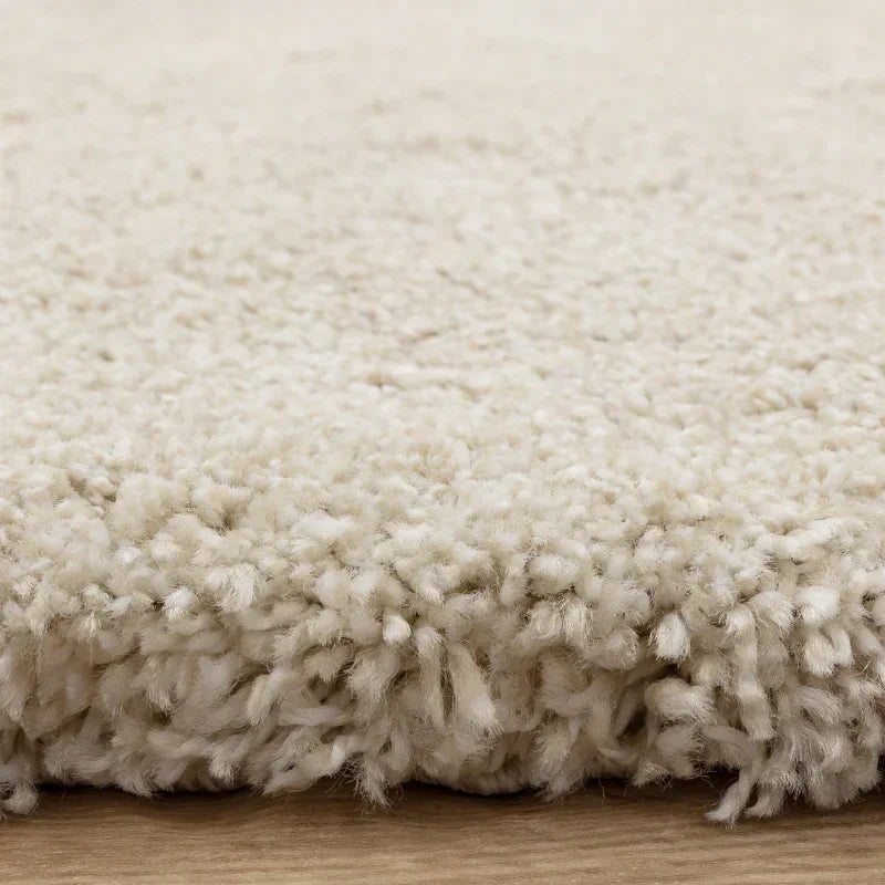 Close side view of cream shaggy rug with thick pile on wood floor