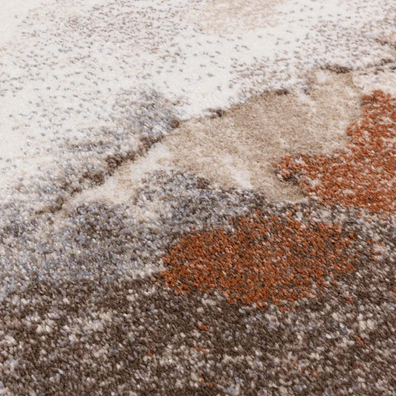 Close-up of modern patterned rug in beige, brown, and rust shades showing soft texture