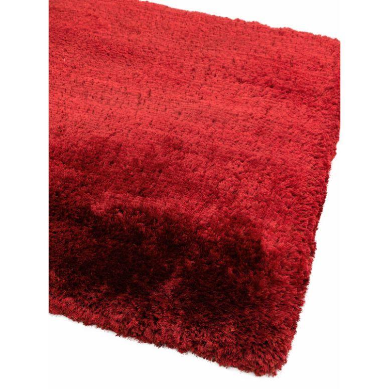 Red shaggy rug with thick pile, close-up of soft textured fibers and finished edge