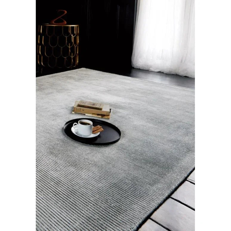Light grey area rug with ribbed texture, tray with coffee cup and book in modern living room
