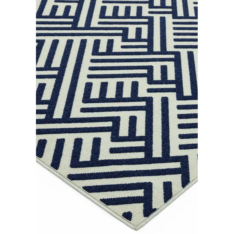 Navy blue geometric patterned rug with cream background and sharp corner view