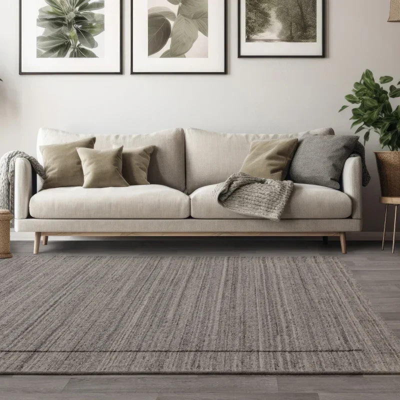 Beige fabric sofa with cushions and throw blanket in modern living room with grey rug