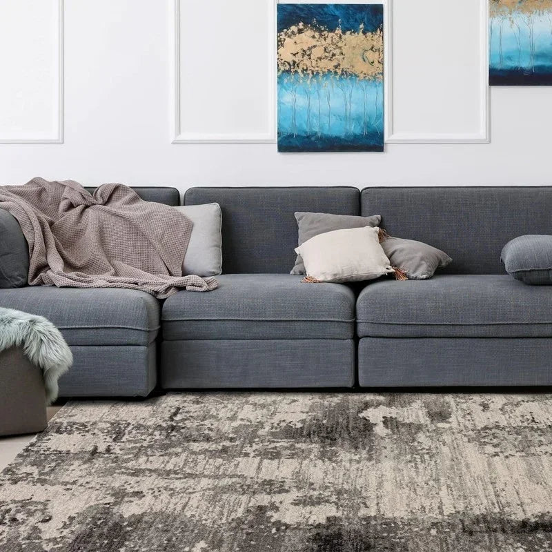 Grey fabric corner sofa with cushions and throw blanket in modern living room setting