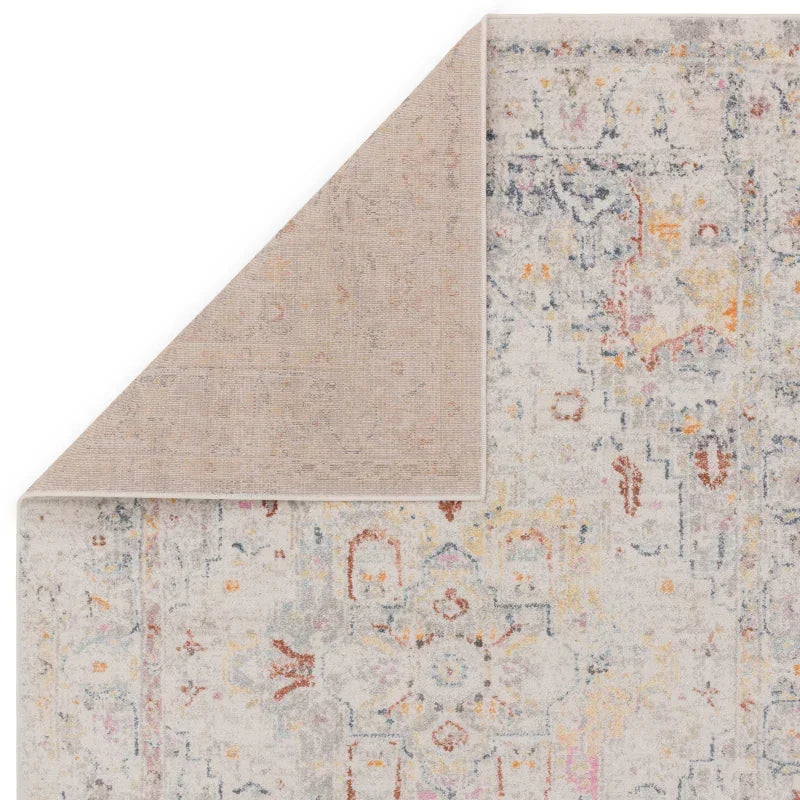 Abstract patterned area rug in soft grey tones with one corner flipped to show backing
