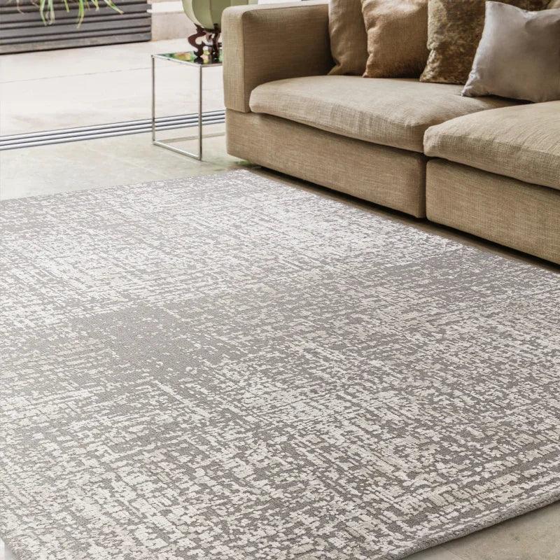 Modern beige area rug with textured pattern beside fabric corner sofa in living room