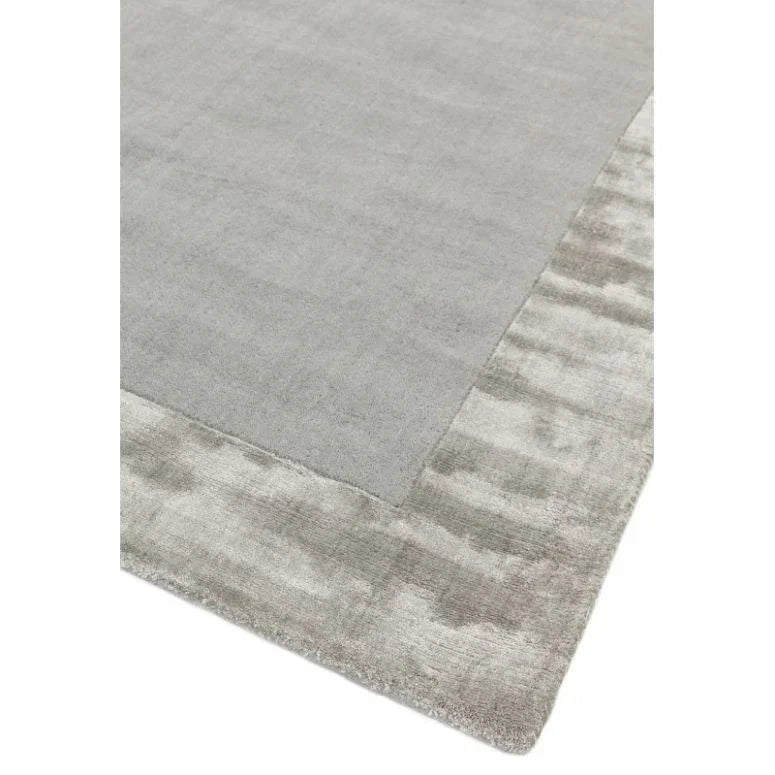 Light grey area rug with textured border and soft finish, corner angle view