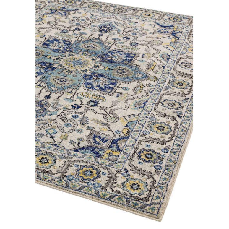 Blue and yellow patterned area rug with distressed floral design, corner angle view