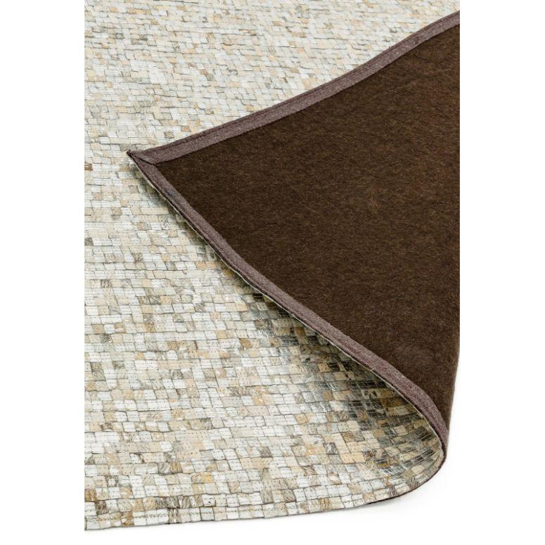 Neutral mosaic pattern rug with corner flipped to show brown felt backing