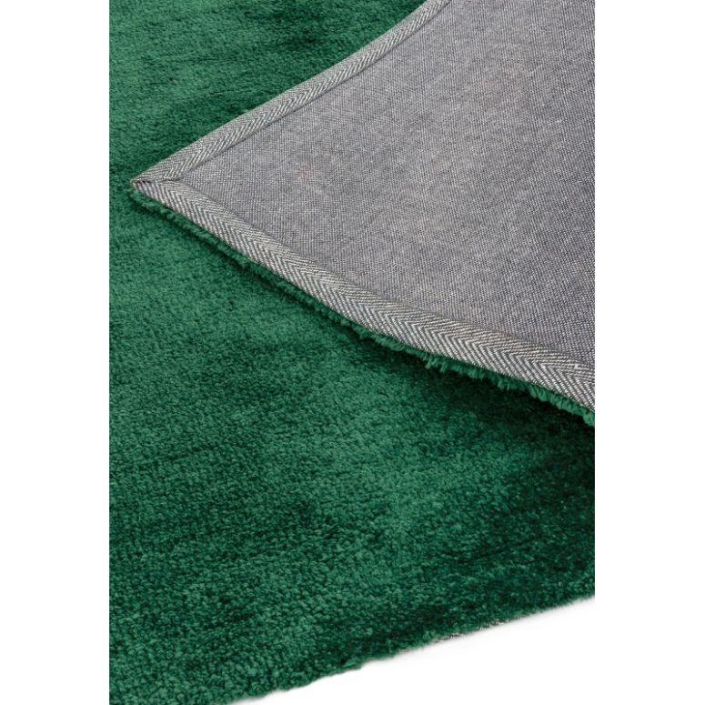 Closeup of green rug with textured pile and visible grey fabric backing