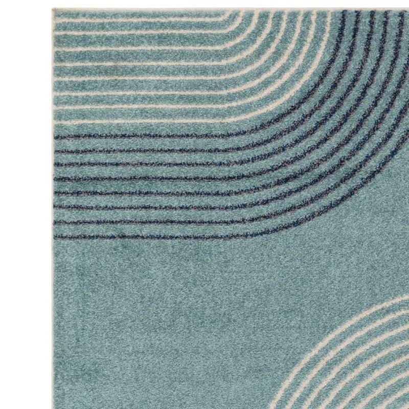 Blue area rug with curved cream and navy line pattern, close-up corner view