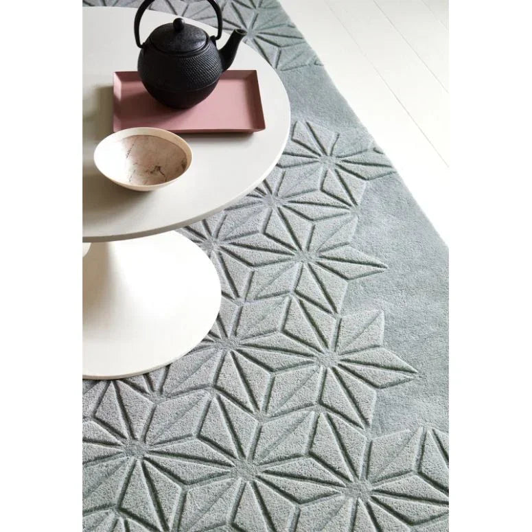 Grey geometric pattern rug with white round table and black teapot in modern living room