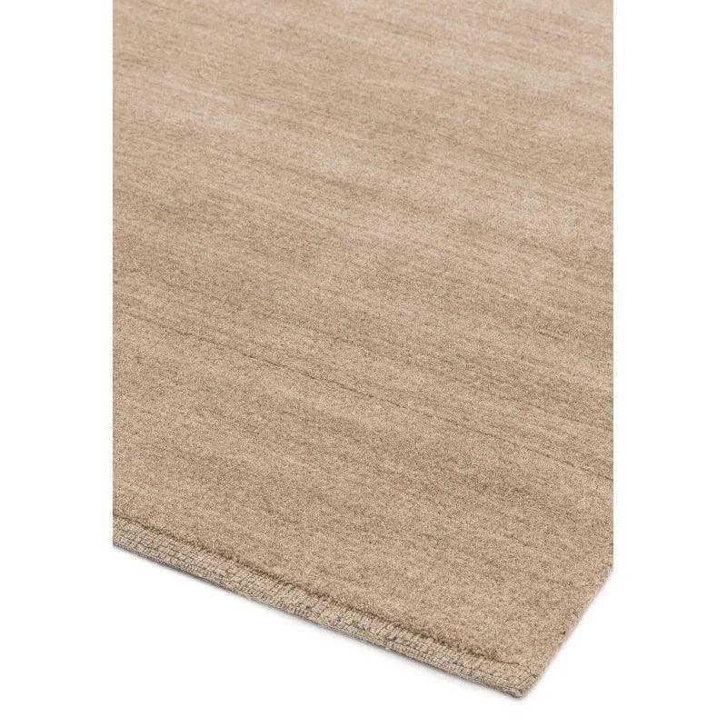 Beige wool rug corner with subtle texture and stitched edge