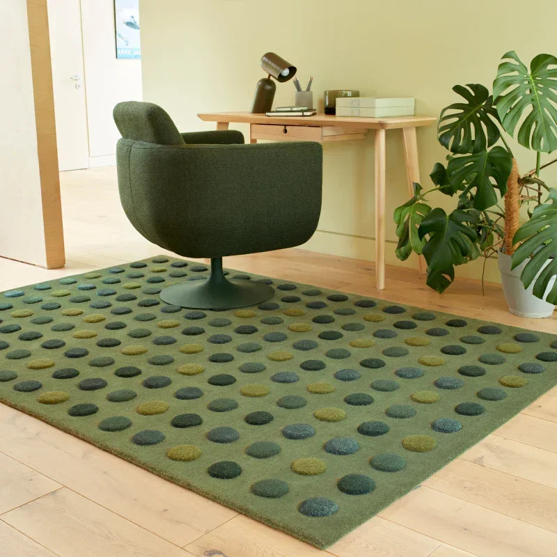 Green polka dot rug under modern green office chair and wooden desk in home office