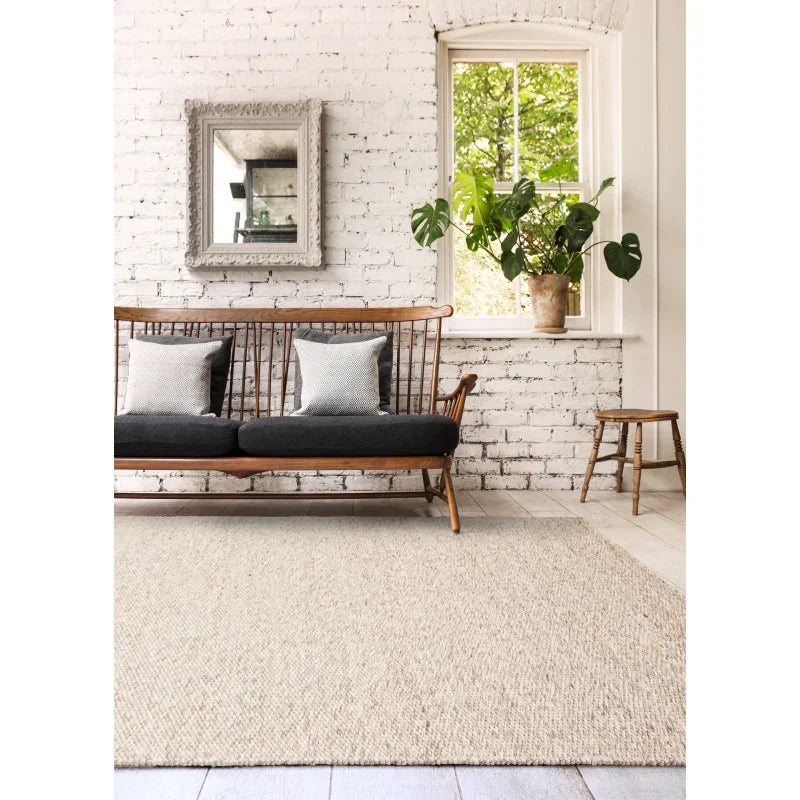 Cream woven rug in living room with wooden sofa, white brick wall, and indoor plant