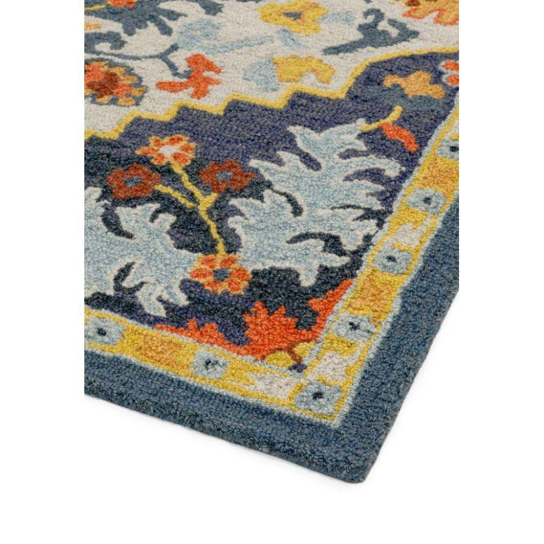 Corner of multicolor wool area rug with floral pattern and yellow border detail