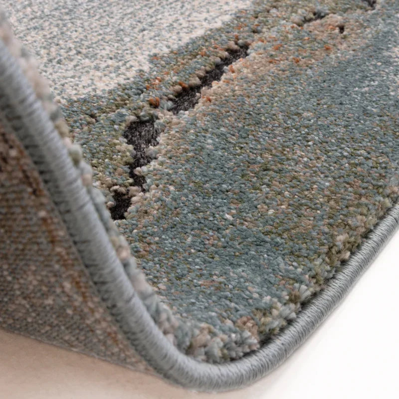 Close-up of soft textured area rug with blue and beige pattern and stitched edging