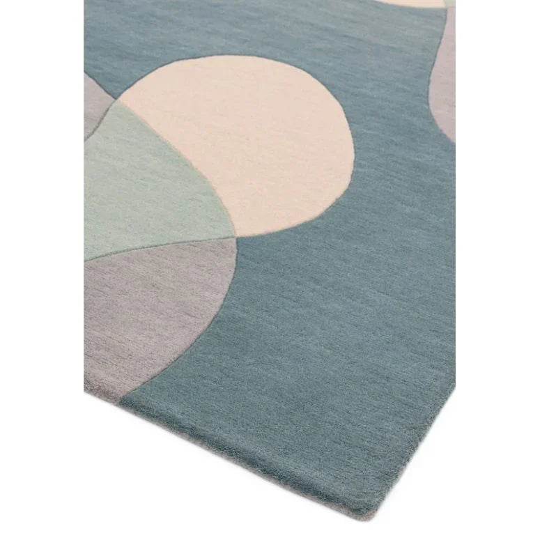 Modern area rug with abstract pastel circles and curved shapes on blue background